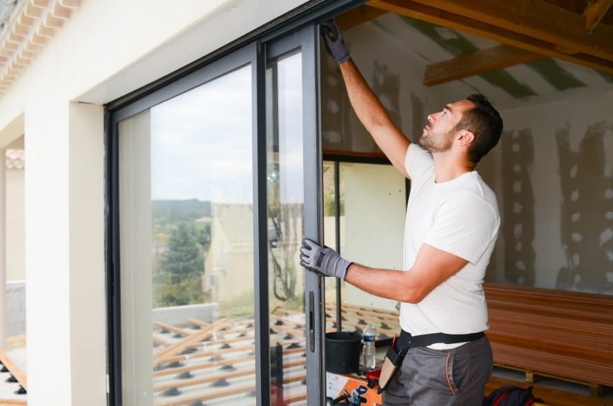 Image depicts the featured image for the blog article Window Replacement 4 Questions to Ask An Installation Company and shows a technician installing a new window in a home.
