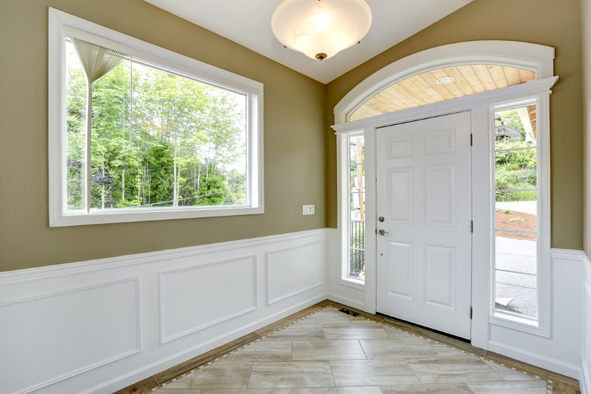 Image depicts a white entry door with sidelites and a transom and vinyl window with white trims.